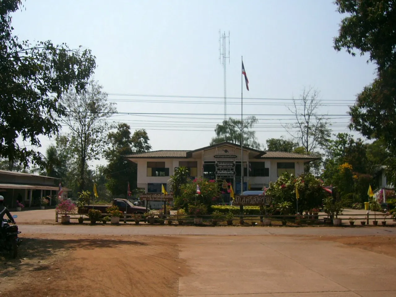 A low provincial police station building set back behind a wide bare forecourt in Nakhon Phanom province