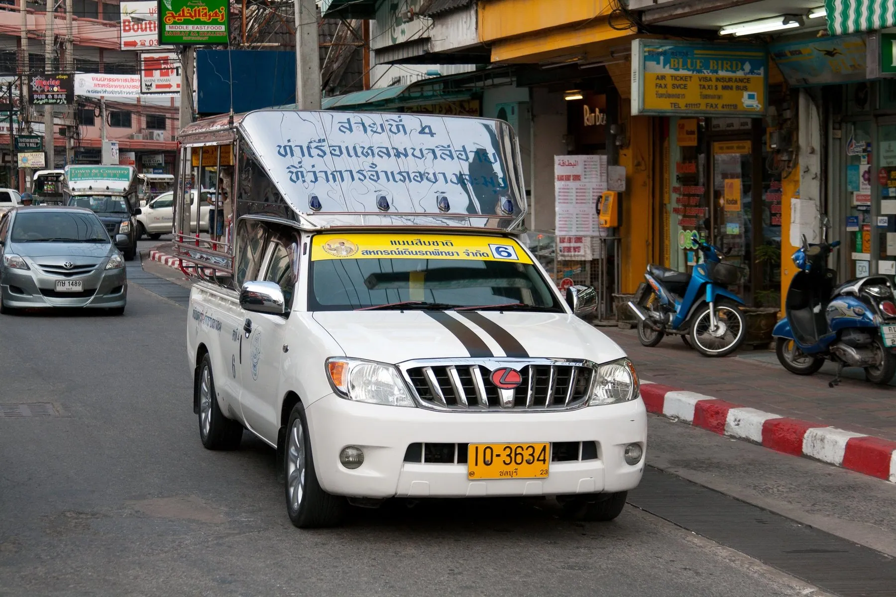 A white songthaew with a route board across its roof stopped in the traffic lane on Pattaya Second Road