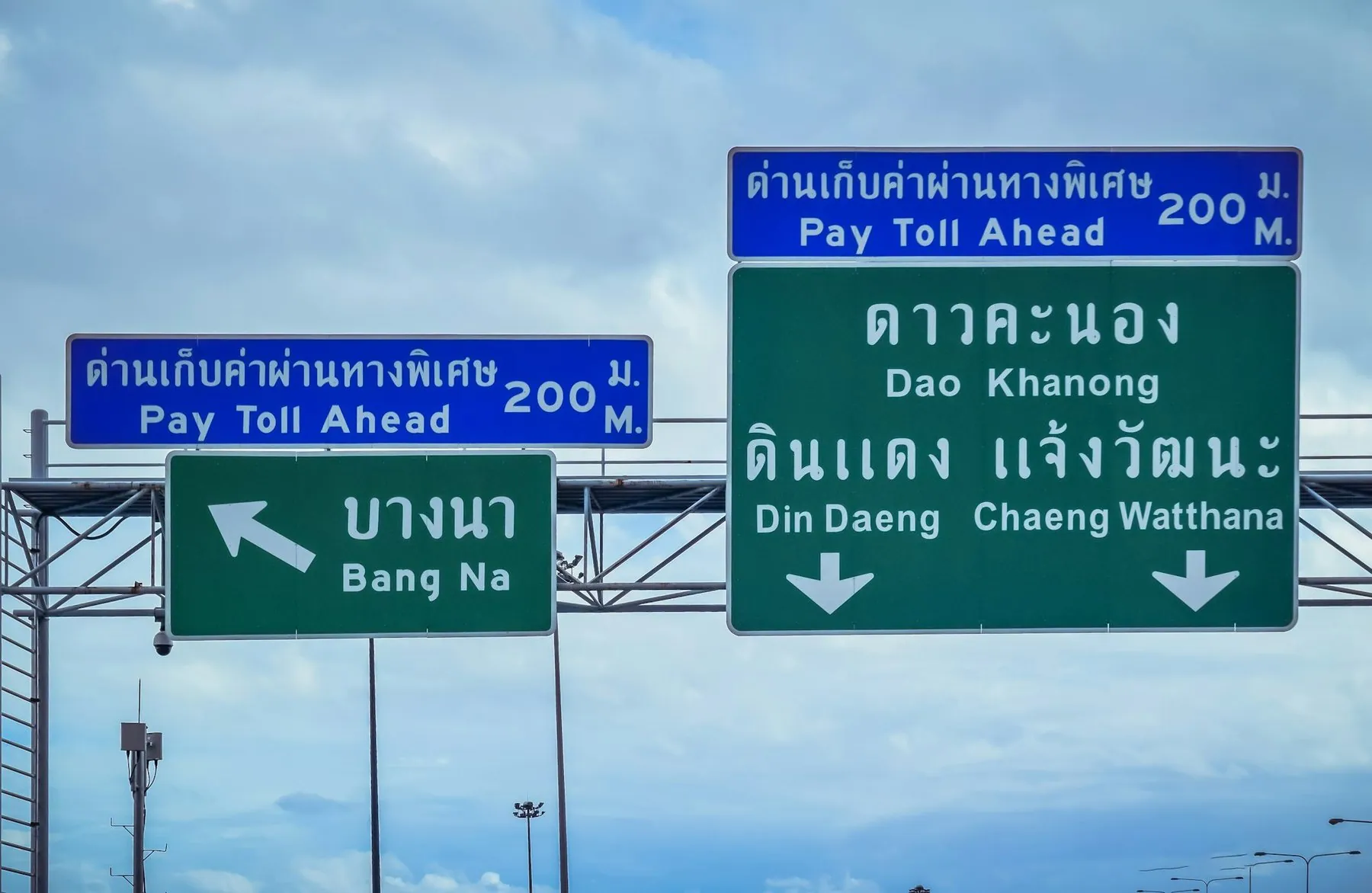 Green and blue Thai motorway gantry signs reading Bang Na, Dao Khanong and Pay Toll Ahead in Thai and English